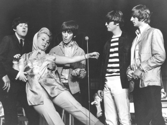 La vida de Zsa Zsa Gabor siempre fue dinámica dentro y fuera de la pantalla aquí en una icónica imagen con los Beatles en 1964, mientras cae en los brazos de Paul McCartney durante un espectáculo de caridad en el London Palladium, Inglaterrra