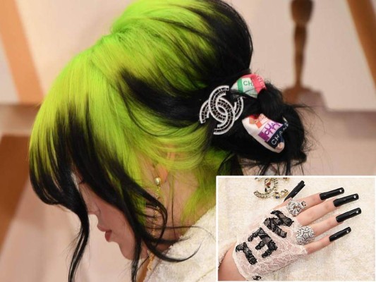 Billie Eilish eligió ir con el pelo en neón y negro, para atarlo, usó varios accesorios coloridos de la firma de alta costura y sus uñas negras súper largas que combinó con guantes de encaje blanco que formaban la palabra 'Chanel' y brillante anillos plateados.
