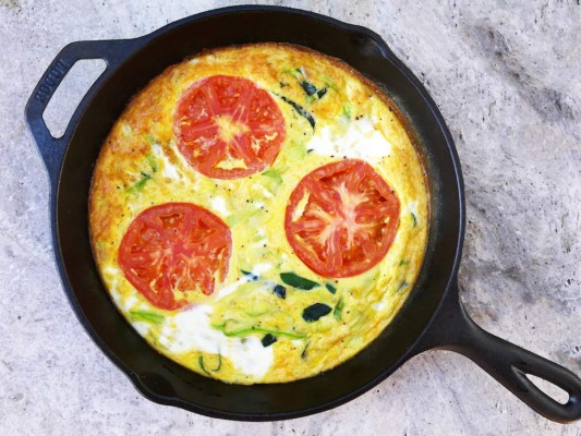 FRITTATA <br/><br/>INGREDIENTES<br/>4 tomates (tres cortados en cubitos y uno reservar entero) /1 cebolla cortada en julianas/ Un zucchini cortado en dados/ Aceite de oliva extra virgen / 4 huevos / 50 ml de leche/ Sal / Pimienta / 25 gramos de queso parmesano<br/><br/>PREPARACIÓN <br/>1/ Calienta una sartén antiadherente ligeramente engrasada con aceite de oliva 2/ Saltea la cebolla, calabacín y tomates, deja que se cocinen y retira de la sartén. Reserva. 3/ En un tazón grande, bate los huevos con la leche. Añade el sofrito de vegetales, queso, sal y pimienta. 4/ Vierte la mezcla en la misma sartén a fuego bajo. 5/ Corta en rodajas el tomate reservado, colócalo en la mezcla y deja que cuaje. 6/ Termina de cocinar en el horno, previamente encendido a 350 grados F. Retira cuando esté dorada. 7/ Sirve bien caliente.<br/>