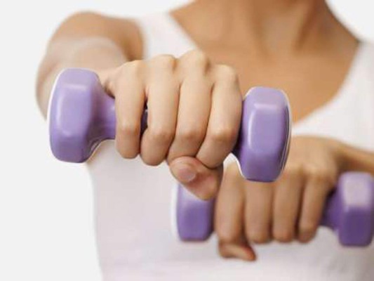 Sentada, toma las pesas con las manos. Extiende los brazos hacia adelante, uno al lado del otro. Sube hasta tocar con el brazo la mejilla. Baja a la postura inicial (a la altura del pecho) y repite con el otro brazo. Haz cinco repeticiones con cada brazo y completa otra serie igual.<br/>