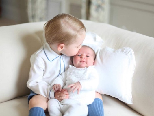 This image made available by Kensington Palace Saturday, June 6, 2015, taken by Kate, Duchess of Cambridge, at Amner Hall, eastern England in mid-May 2015 shows Britain's Princess Charlotte, right, being held by her brother, 2-year-old, Prince George. Britain’s royals have been photographed by some of the world's leading photographers. But Prince William and Kate are continuing a more informal tradition begun two years ago with the first official portrait of Prince George, taken by his grandfather Michael Middleton. Charlotte was born May 2 and is fourth in line to the throne. (Duchess of Cambridge via AP) MANDATORY CREDIT