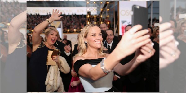 Reese Witherspoon, se toma un selfie mientras el público tras ella, la saluda emocionado para también salir en su imagen.