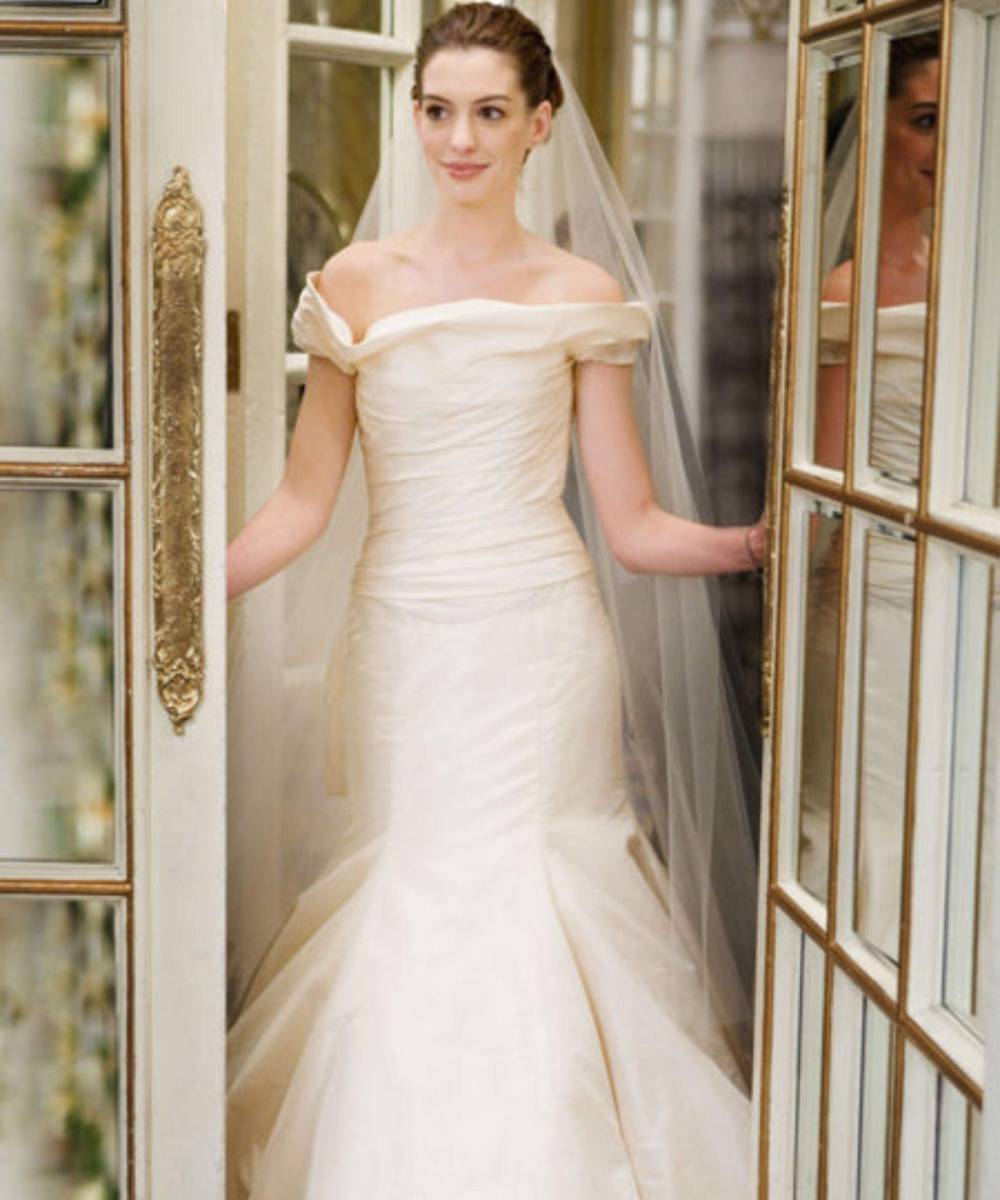 Guerra de NoviasEn esta película, que salió en 2009 y en la que compartió el protagónico con Kate Hudson, podemos ver a Anne Hathaway con un vestido de novia sencillo con cuello tipo barco con drapeado en el corpiño y un velo que se desliza desde la parte baja de su cabeza. ¡A esta chica sí que le lucen los vestidos de novia! 