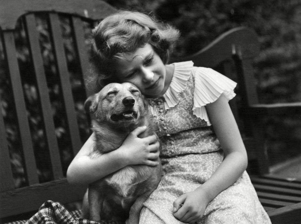 Isabel II, a los 10 años, abraza a uno de sus corgis en su casa en 1936.
