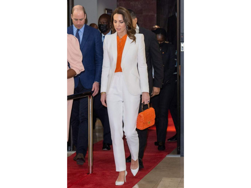 Para el día siguiente, Kate Middleton utilizó un traje completo color blanco, el que complementó con toques de color naranja en su blusa y bolso.