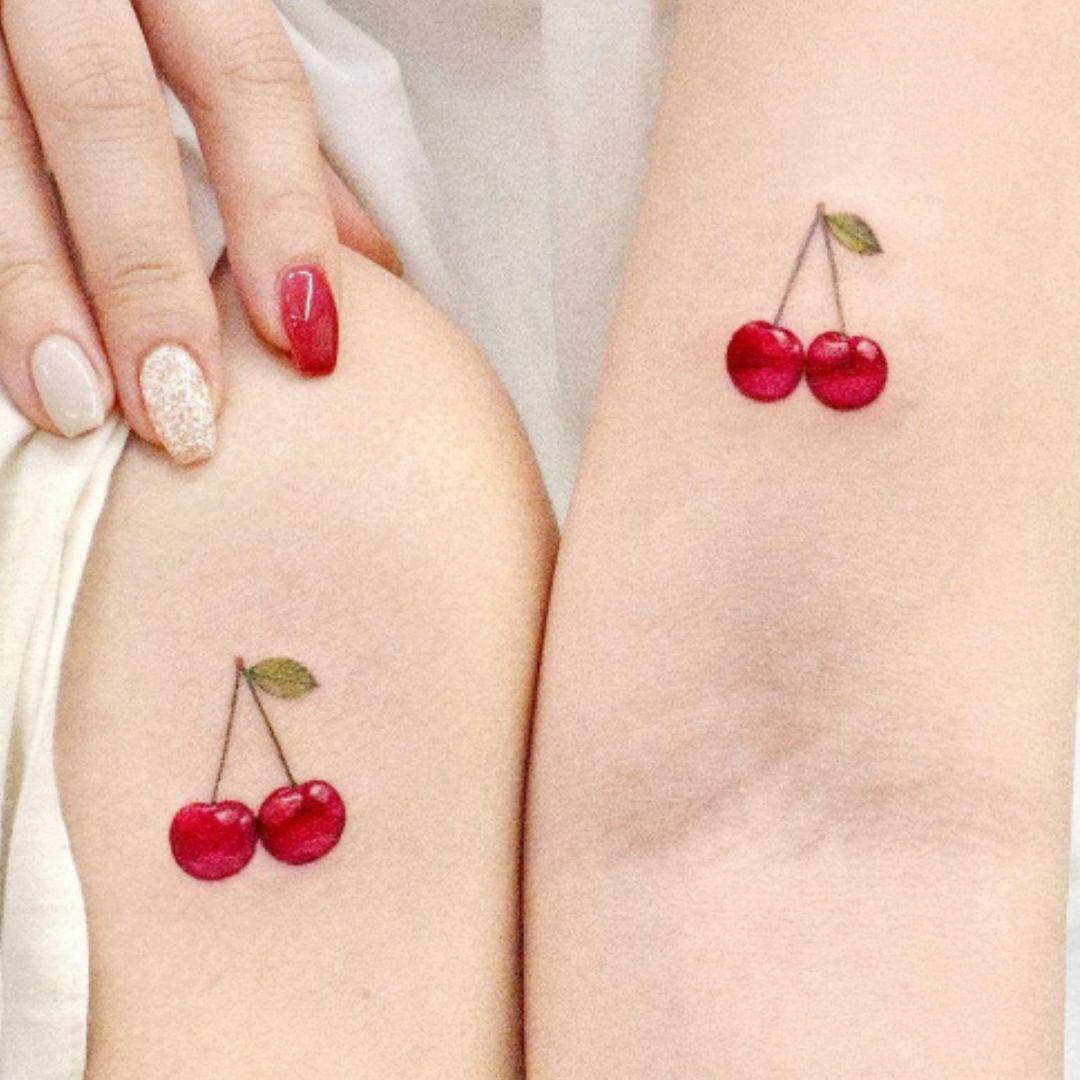 Este tatuaje de cerezas jugosas es una excelente manera de jugar con el color sin perder el romanticismo y la dulzura. Puedes elegir una cereza cada uno para formar una pareja o hacer una pareja doble.