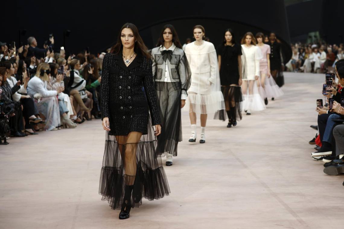 La Semana de la Moda de París anuncia un invierno sofisticado y glamoroso. Como un teatro de ilusiones oníricas, la colección Prêt-à-Porter Otoño-Invierno 2025/26 de CHANEL, presentada por el Estudio de la Creación, juega con escalas de tamaño, longitud y proporción. Bajo el techo de cristal del Grand Palais, una instalación diseñada por el escenógrafo Willo Perron y con una cinta negra como telón de fondo monumental, la colección se inclina hacia puntos de referencia y altera las percepciones.