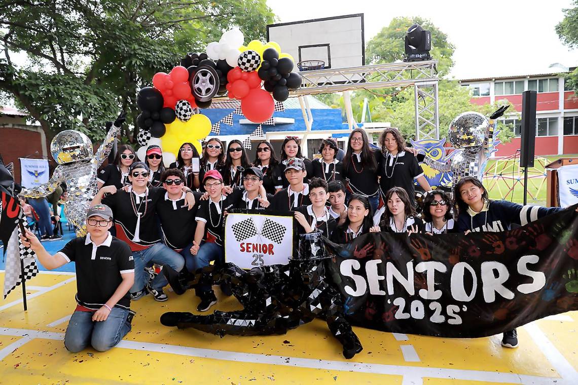 Los rayos del sol iluminaron el emocionante comienzo de clases para la generación 2025 de Summer Hill School. Bajo el tema “There’s Still One Race to Win”, los seniors se prepararon para enfrentar su último año escolar con determinación. Luciendo coloridas camisetas, abordaron pickups y autos deportivos para iniciar una caravana hacia el centro educativo. Allí, fueron recibidos con aplausos y vítores, dando inicio a un día lleno de emociones y celebración.