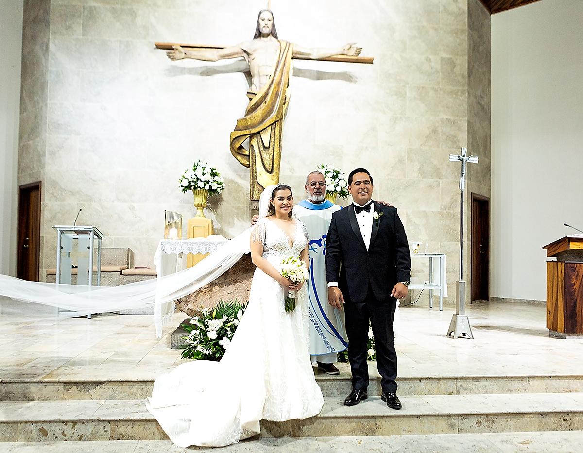 Cindy Osorto y Miguel Lanza posan en el altar del templo San Juan Bosco junto al sacerdote Ronal Córdova 