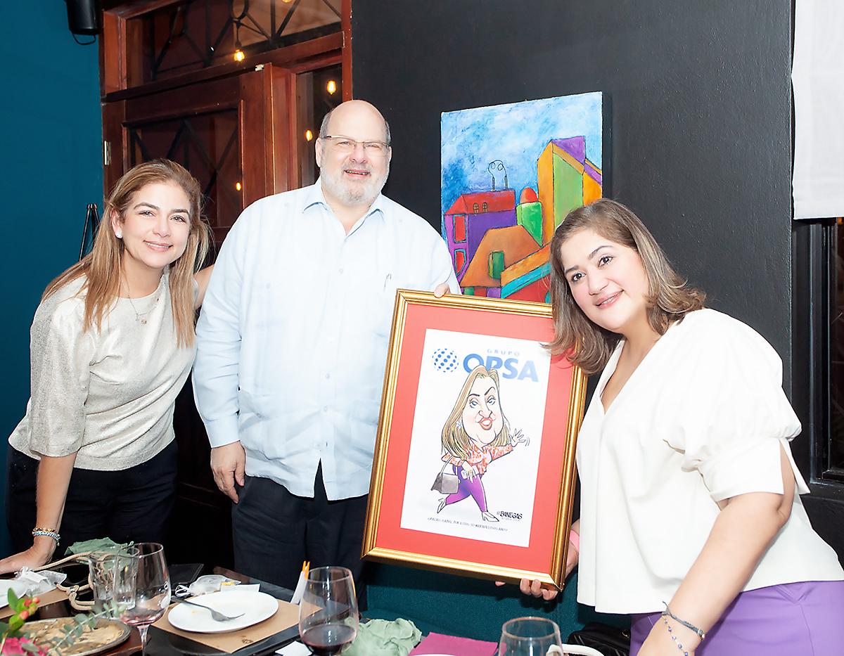 Ruth Marie Canahuati y Jorge Canahuati hacen entrega de una caricatura a Isabel Sabillón como recuerdo de su impecable carrera en Opsa