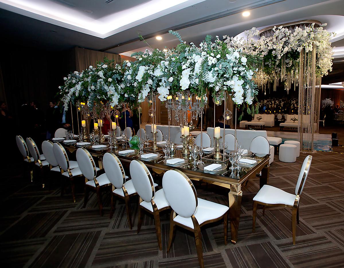 Una decoración moderna y elegante con elementos como mesas imperiales y sillas Catalina, arreglos en bases de metal con hermosos arreglos.
