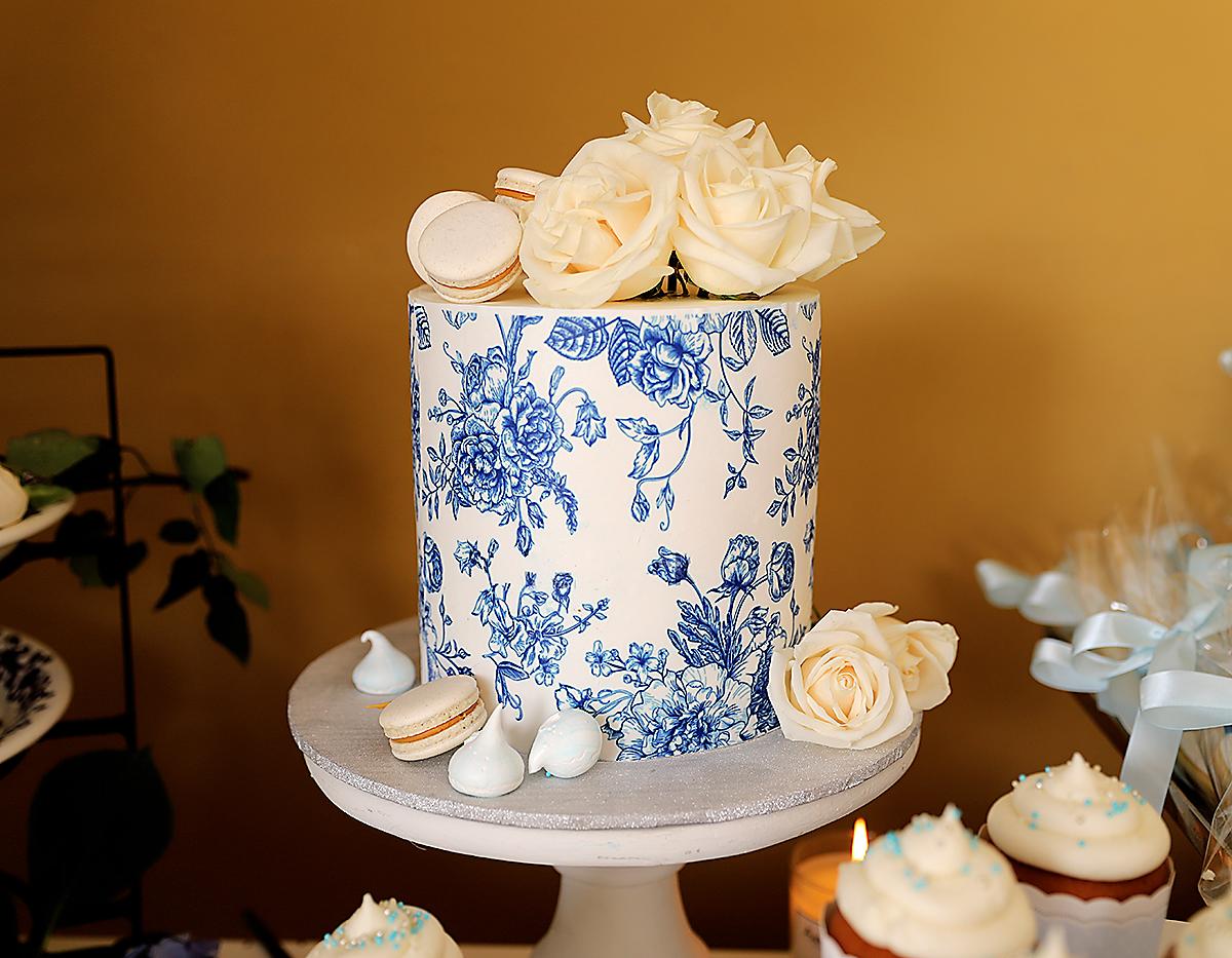 Delicado pastel con diseño de flores y acompañado con macarrones que completan la obra.