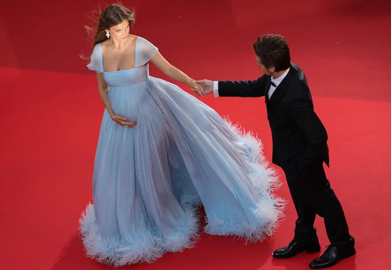 La futura madre se aseguró de que su reveal fuese con estilo: ella lució un vestido suelto y azulado de Miu Miu, con plumas que decoraban finamente el bajo y usando joyería con luminosos diamantes de Chopard.