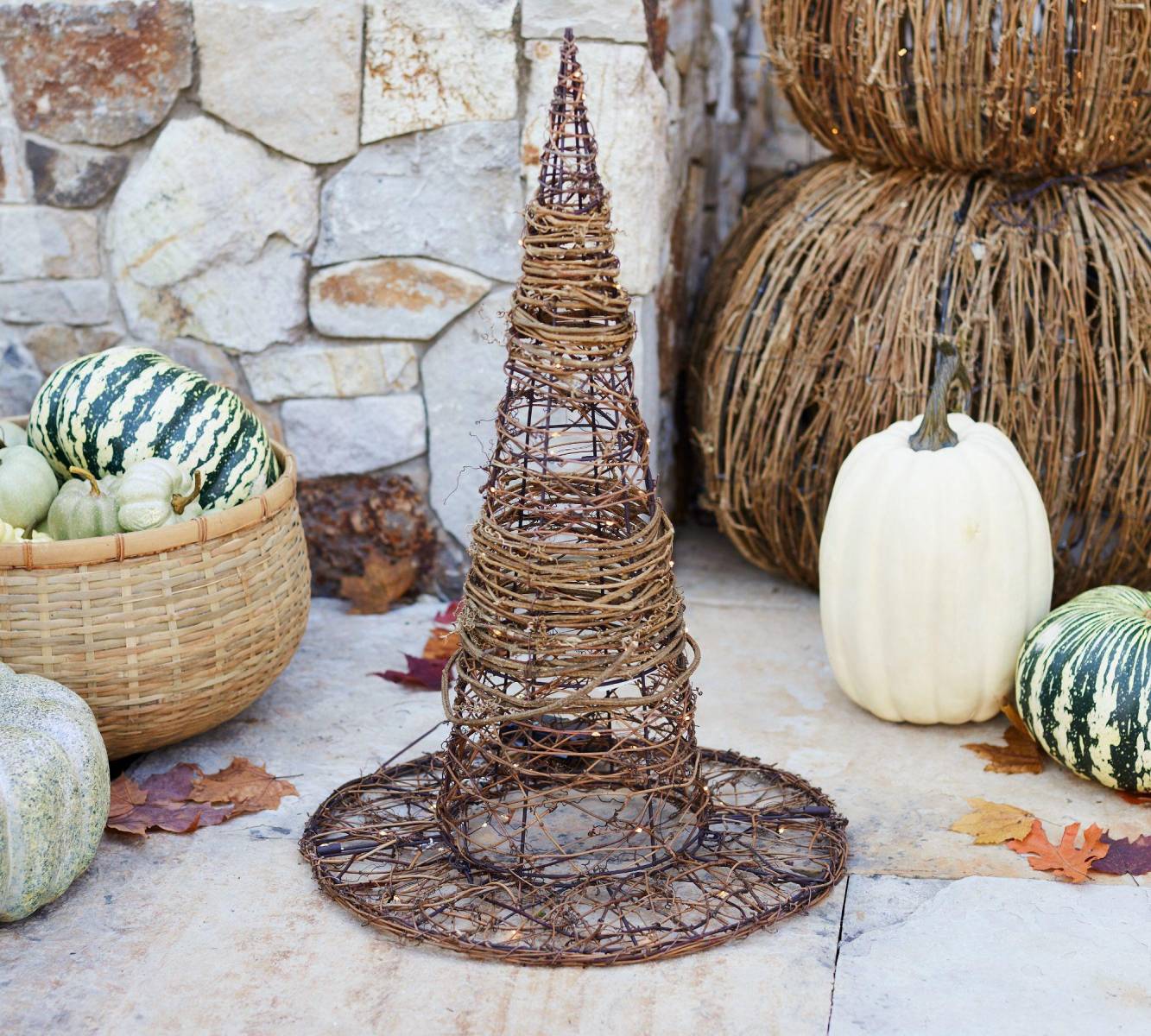 Escultura tejida traza la forma del sombrero puntiagudo de una bruja en el aire. Elaborado con alambre envuelto en ratán, se puede utilizar para iluminar y decorar el rellano de una escalera, el porche o junto a la puerta del jardín. 