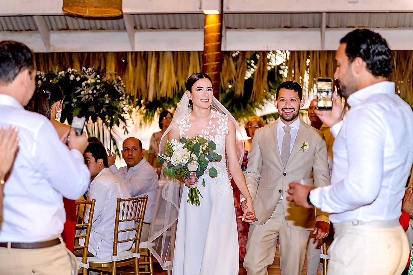 Stephanie y Daniel entran radiantes de alegría a la recepción nupcial en San Simón Beach Club.