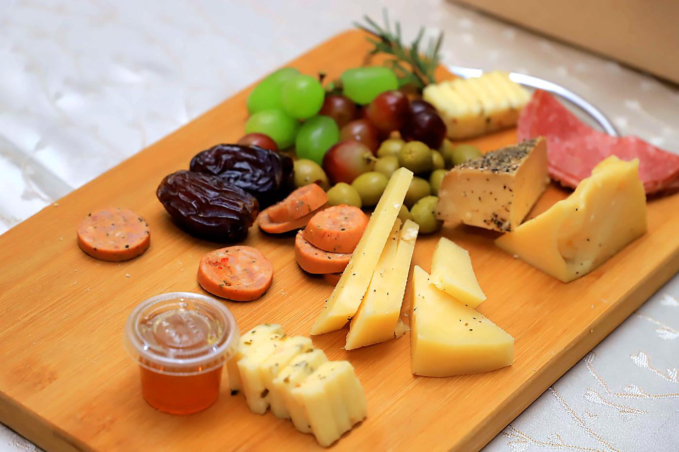 Tabla con quesos, frutas, semillas, jamones y mermelada para ser preparados.