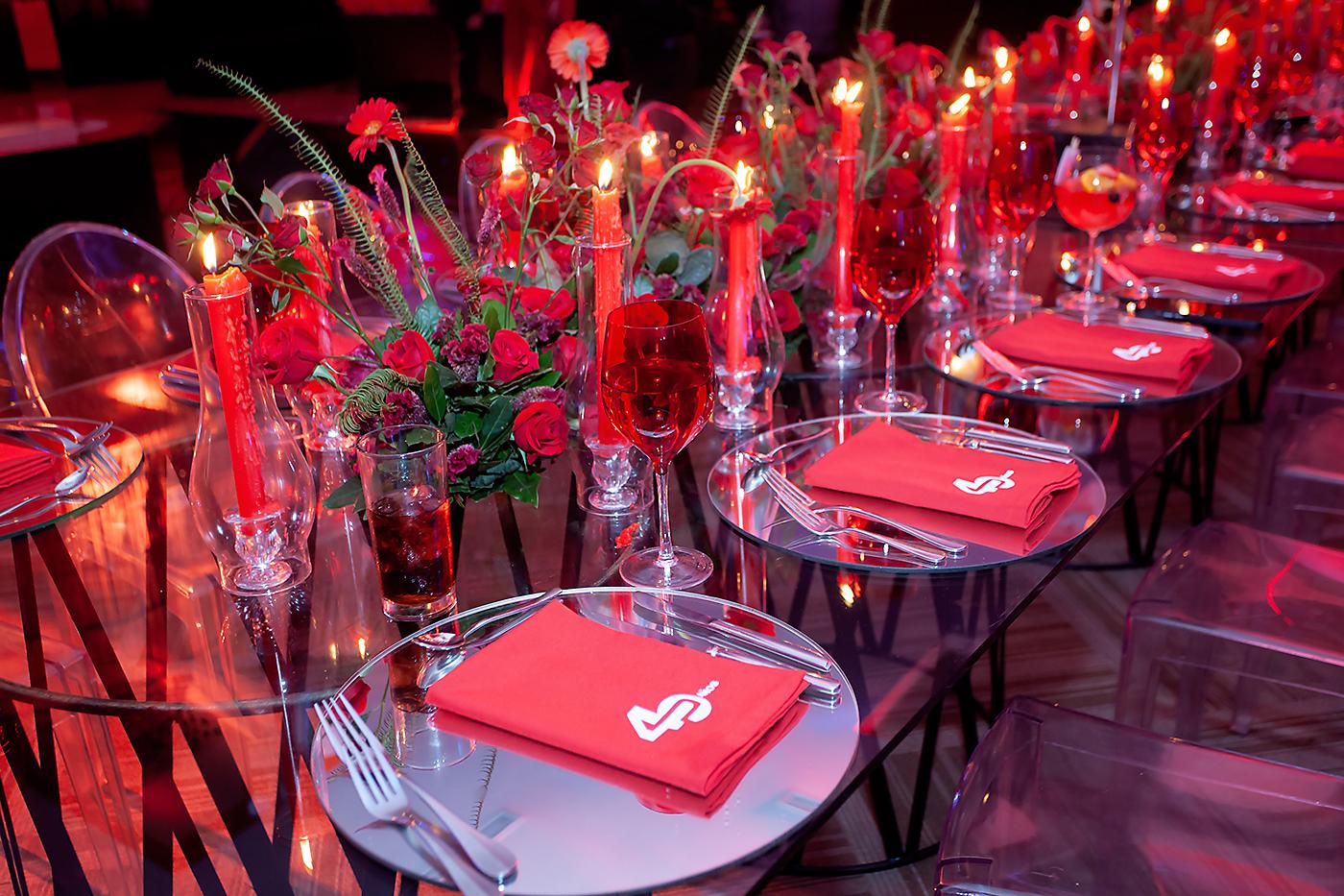 Las mesas rectangulares estaban adornadas con candelabros estilo quinque con velas rojas que hacían juego con los arreglos de rosas rojas.