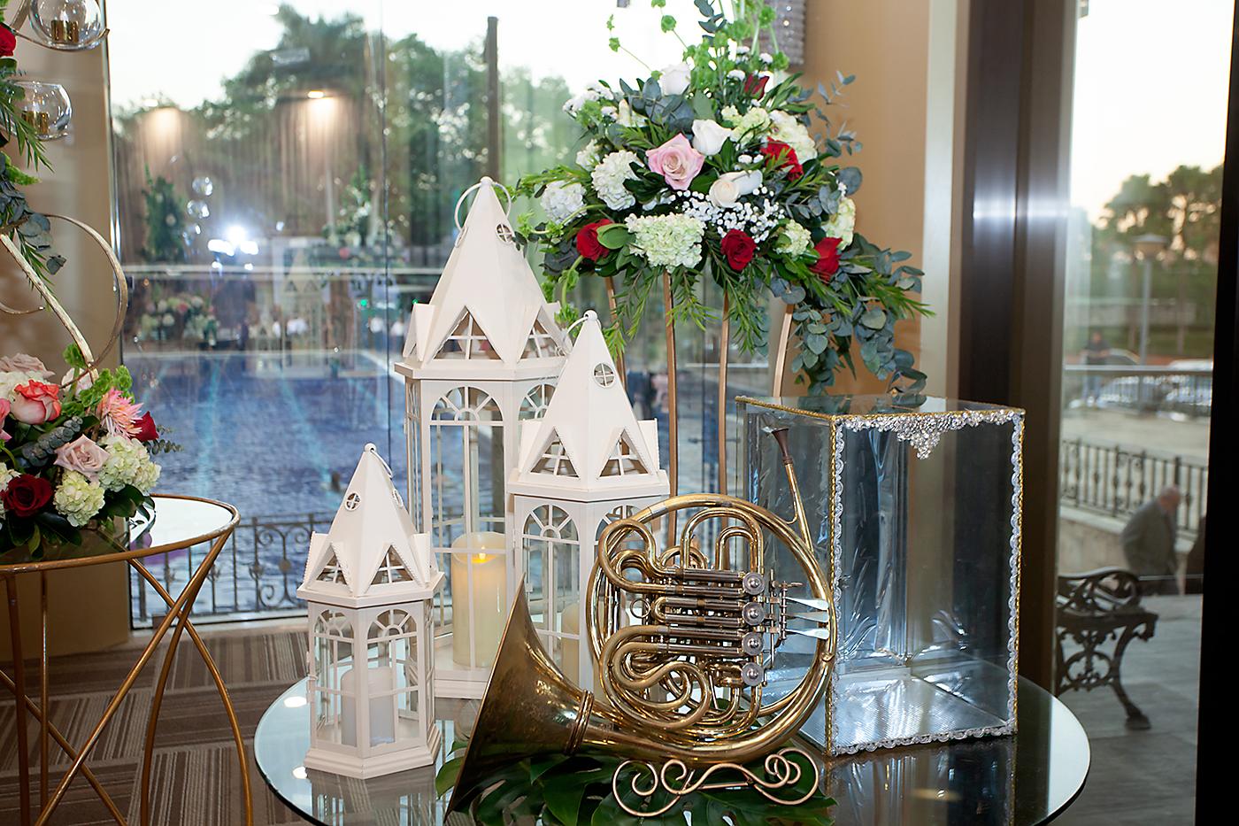 En la entrada al salón ubicaron una mesa, la cual adornaron con un hermoso arreglo floral, candelabros de metal, una trompa instrumento predilecto de la novia.