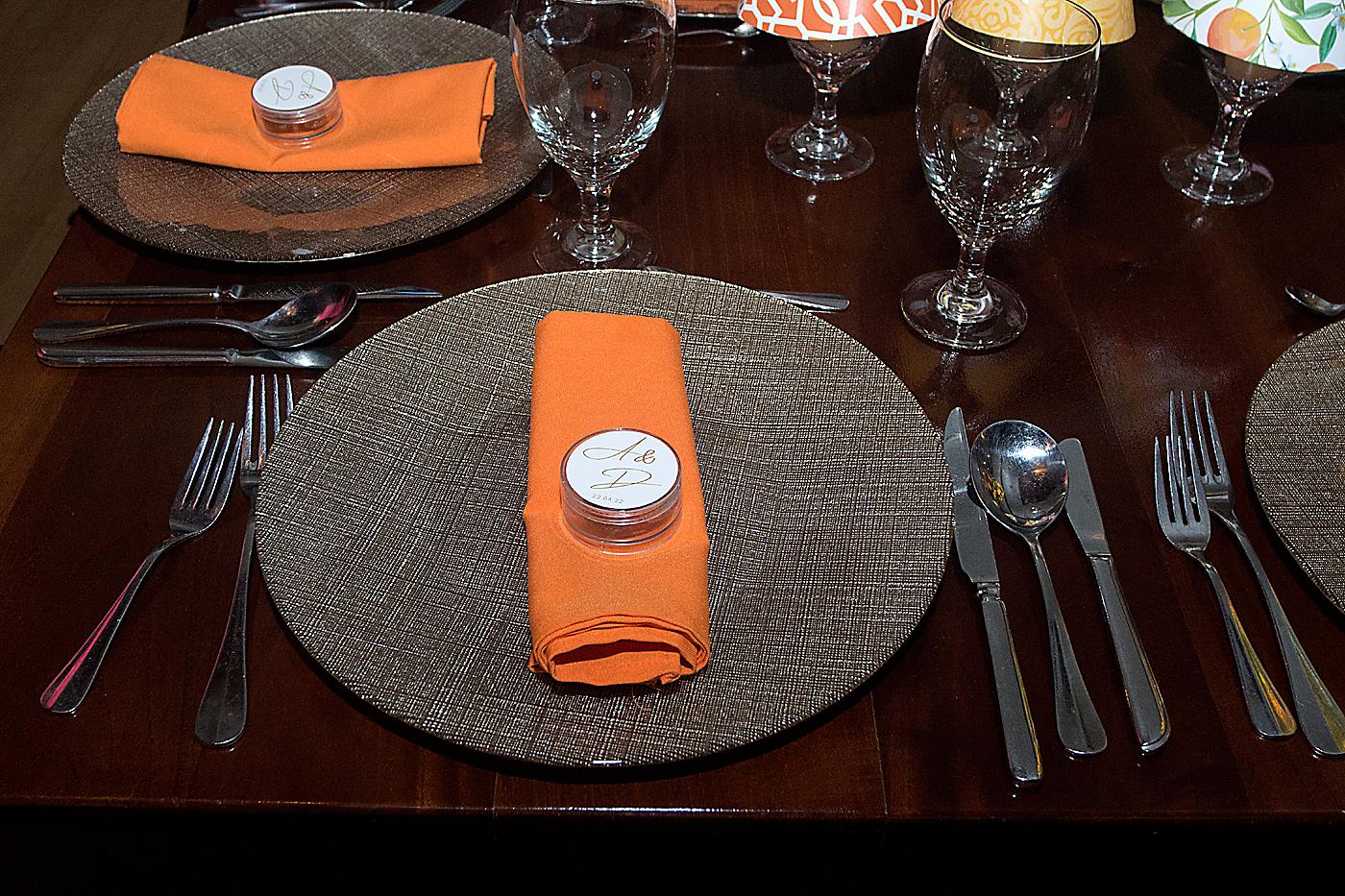 Base de vidrio con su respectiva servilleta en tono naranja y detalle con las iniciales de los novios.