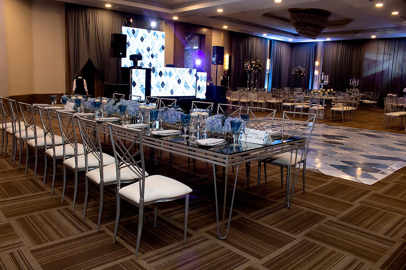 La organización del evento estuvo a cargo de Susana Prieto y su equipo, quienes integraron mesas rectangulares espejadas con arreglos de diferentes alturas y otras con candelabros con hortensias, rosas y follaje. Para losjóvenes se acondicionó una área moderna tipo disco con salas lounge 