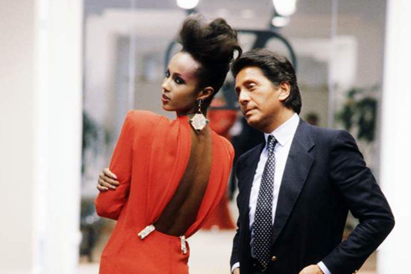 Valentino Garavani junto a una creación de alta costura en rojo, temporada Otoño 1984.