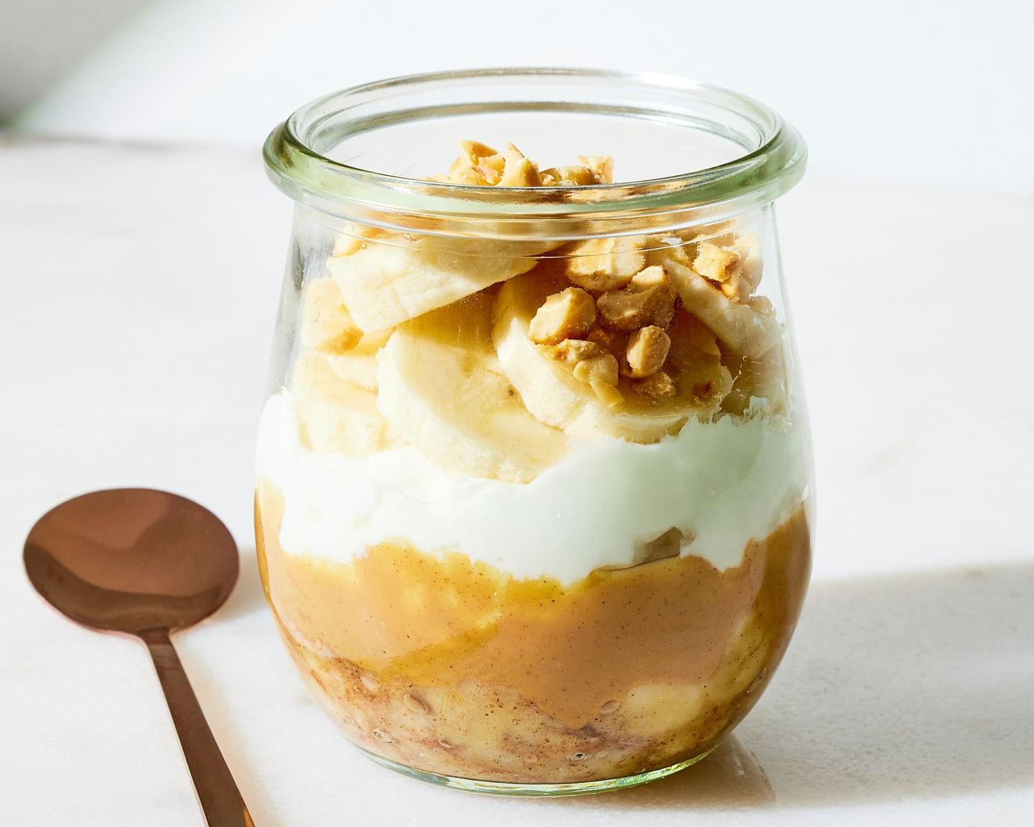 Pica una banana y coloca la mitad en un recipiente pequeño, espolvoreando canela y moliendo con un tenedor. Encima, coloca una cucharada de peanut butter seguida de ¼ de taza de yogur. Decora con el resto del banano y el topping de tu gusto, y disfruta de un postre que te aportará proteína y grasas saludables.