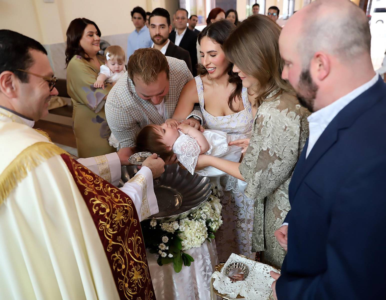 Con agua bendita y esperanza, el sacerdote le dio la bienvenida a las niñas a la vida cristiana. Bella con sus padres y padrinos María José Agüero y Álex Herzog.