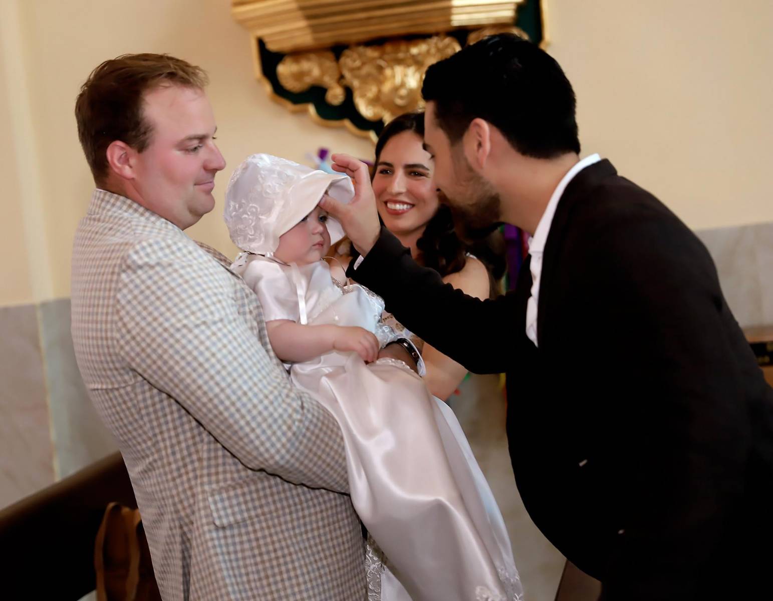 Momento en que el padrino Miro Cuculiza traza la señal de la cruz sobre su ahijada, sellando con amor su compromiso de guiarla en la fe.