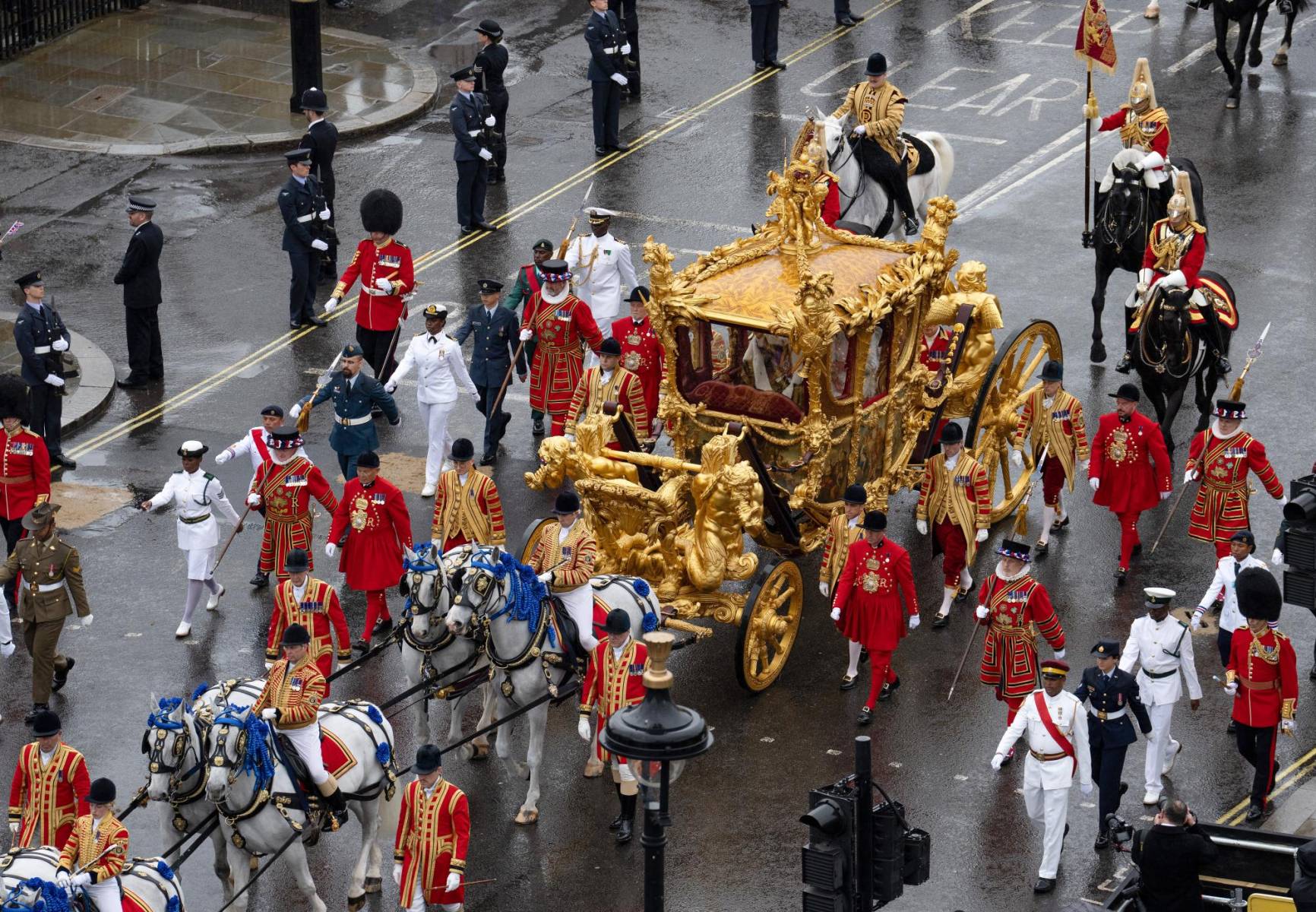 Los reyes de Inglaterra recorren Londres en la Gold State Coach, construida en 1762 <b>en madera recubierta</b> por una capa de pan de oro y adornada con paneles pintados de dioses romanos y tres querubines en el techo que simbolizan Inglaterra, Escocia e Irlanda. 