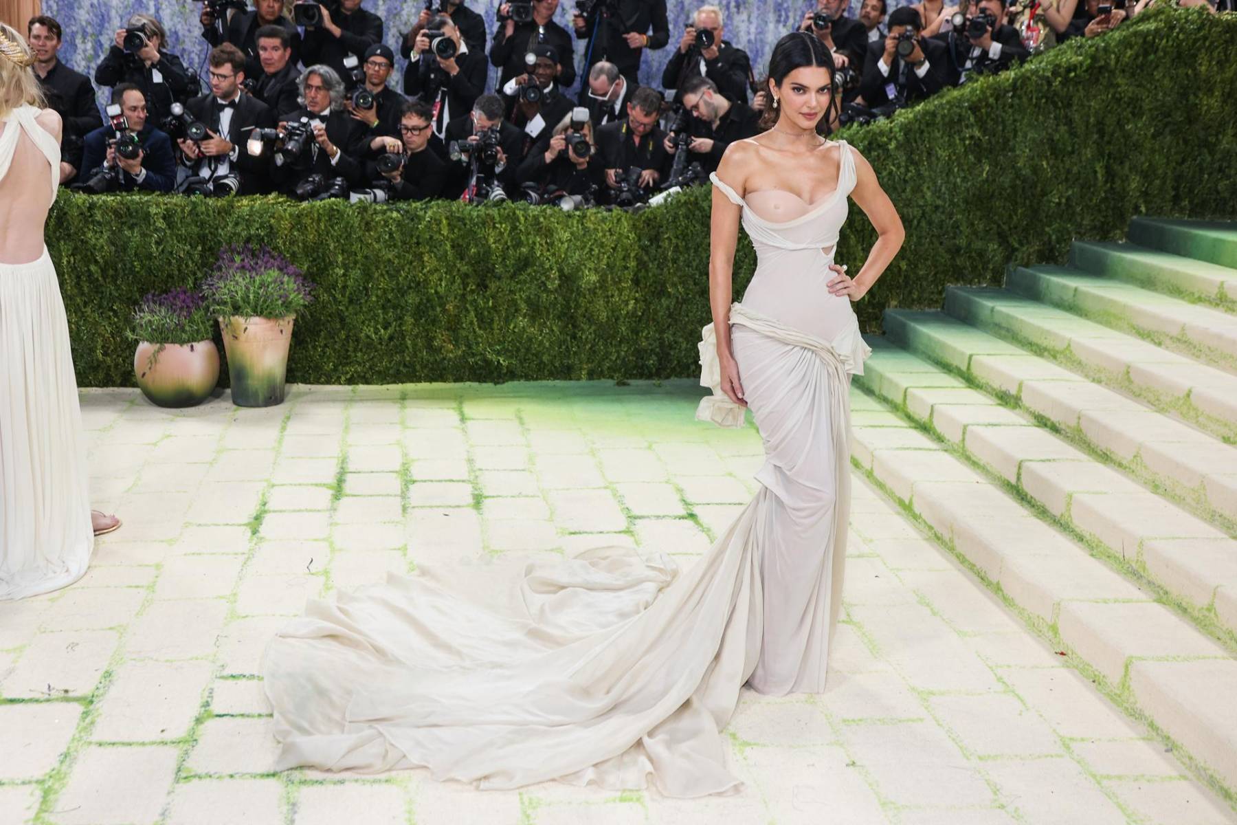 Kendall Jenner lució un diseño exclusivo de Zac Posen para GapStudio. Se trata de un vestido nude con escote revelador, inspirado en la escultura de la Victoria Alada de Samotracia, confeccionado con técnicas de corsé 3D y drapeado asimétrico.