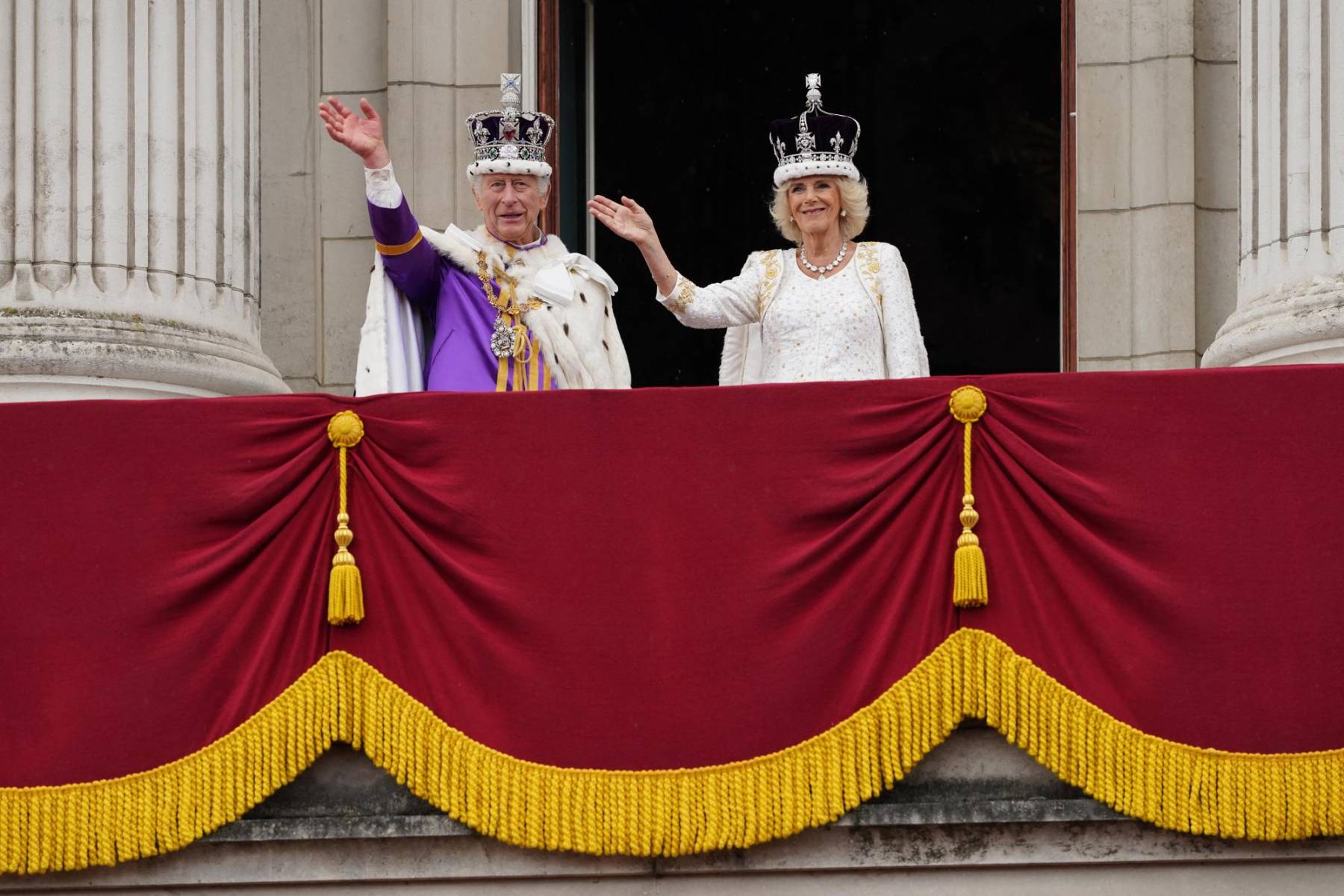 Portando la corona de San Eduardo, Carlos III de 74 años saluda al público junto a su esposa Camila de 75 años previo al desfile aéreo, acortado por el mal tiempo