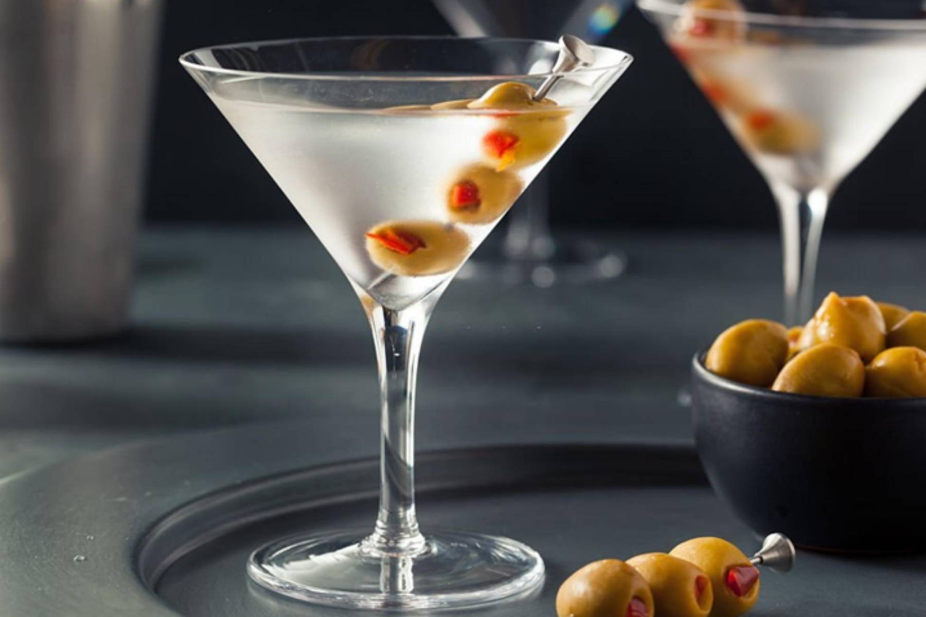 <b>Martini Dry: </b>Es uno de esos cócteles que ha resistido la prueba del tiempo, siempre elegante y sofisticado. Sus ingredientes básicos son vermú blanco, ginebra y una aceituna, pero las proporciones pueden variar según los gustos personales. El origen del Martini es algo incierto; algunas historias lo vinculan a Nueva York, donde el barman del Hotel Kilmanac lo preparaba para el multimillonario Rockefeller, mientras que en el pueblo Martínez, en San Francisco, reclaman su paternidad. Para prepararlo, mezcla 60 ml de ginebra y 15 ml de vermú blanco en un vaso mezclador con hielo. Remueve bien, cuela y sirve en una copa de cóctel fría, decorada con una aceituna. Un aperitivo perfecto para cualquier ocasión.