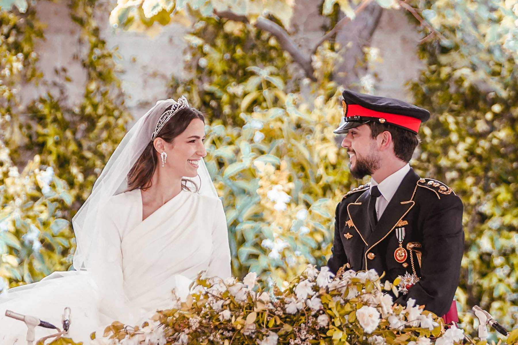 El príncipe Hussein y su esposa Rajwa al-Seif quien lució radiante con un diseño de Alta Costura de Elie Saab que complementó con un extenso velo con bordados y tiara de diamantes diseñada por Yan Sicard de la joyería FRED Paris y que fue usada previamente por su ahora suegra, Rania de Jordania (Photo by Jordanian Royal Palace / AFP)