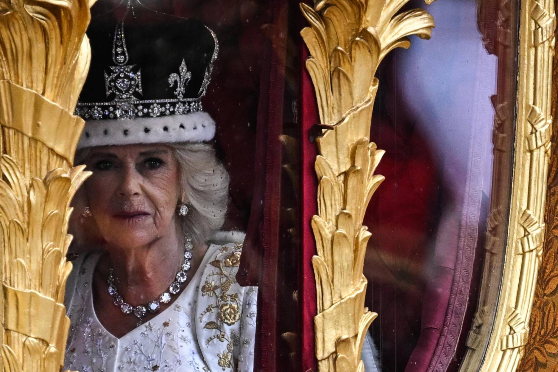 Camila, reina consorte, luce la corona encargada por la reina María de Teck, abuela de Isabel II, a la joyería Garrad y que está compuesta por ocho arcos. Además lleva la túnica de terciopelo que Isabel II utilizó en 1953 en su coronación.