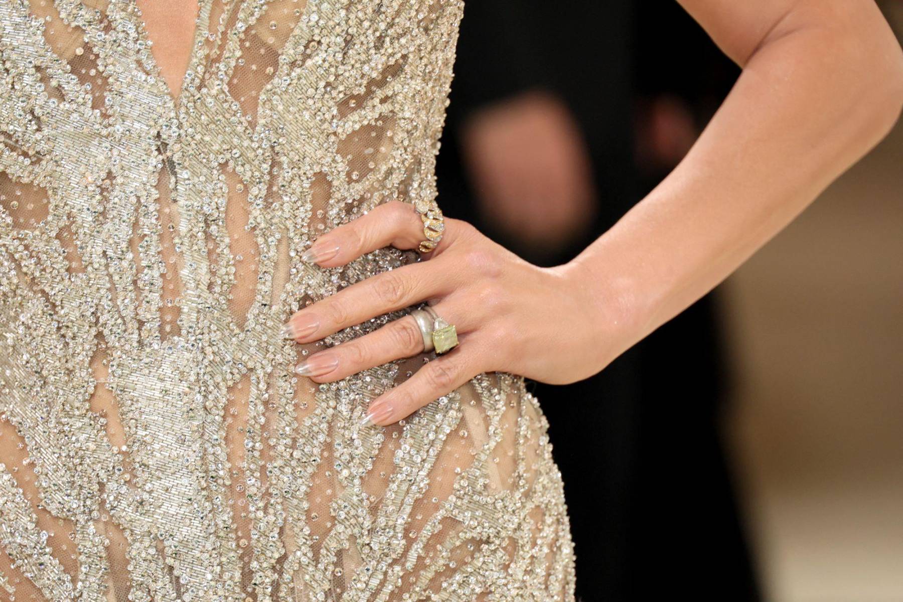 Uñas nude y anillos dorados, a tono con el vestido bordado 