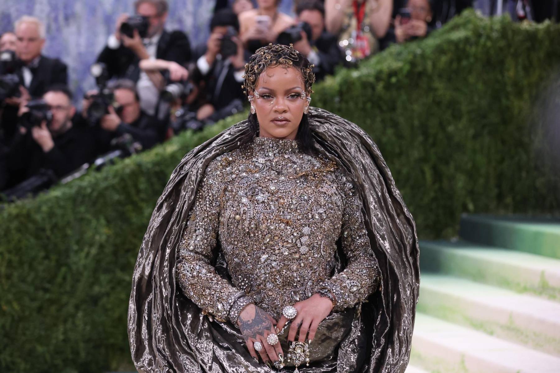 En la Met Gala 2026, Rihanna protagonizó una de las apariciones más comentadas de la noche gracias a un look de alta costura de Maison Margiela que apostaba por una silueta monumental, con capas arquitectónicas y un abrigo estructural de proporciones casi escenográficas, que convertía cada paso en una declaración visual. 