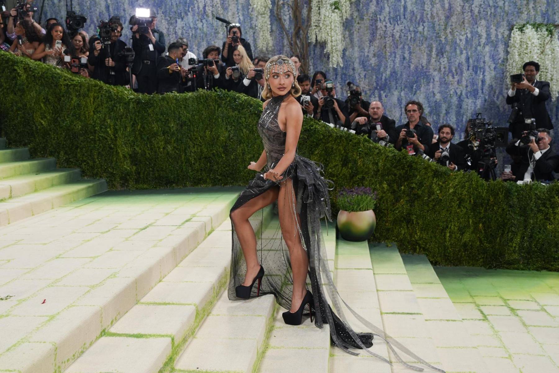 Sabrina Carpenter se inspiró en un clásico del cine del Viejo Hollywood, la película Sabrina (1954). La cantante llevó un vestido de tul creado por Jonathan Anderson para Dior. El look rinde homenaje a la película protagonizada por Audrey Hepburn, que se acentuaba aún más por la envoltura de todo el cuerpo en tiras de película incrustadas con diamantes de imitación. 