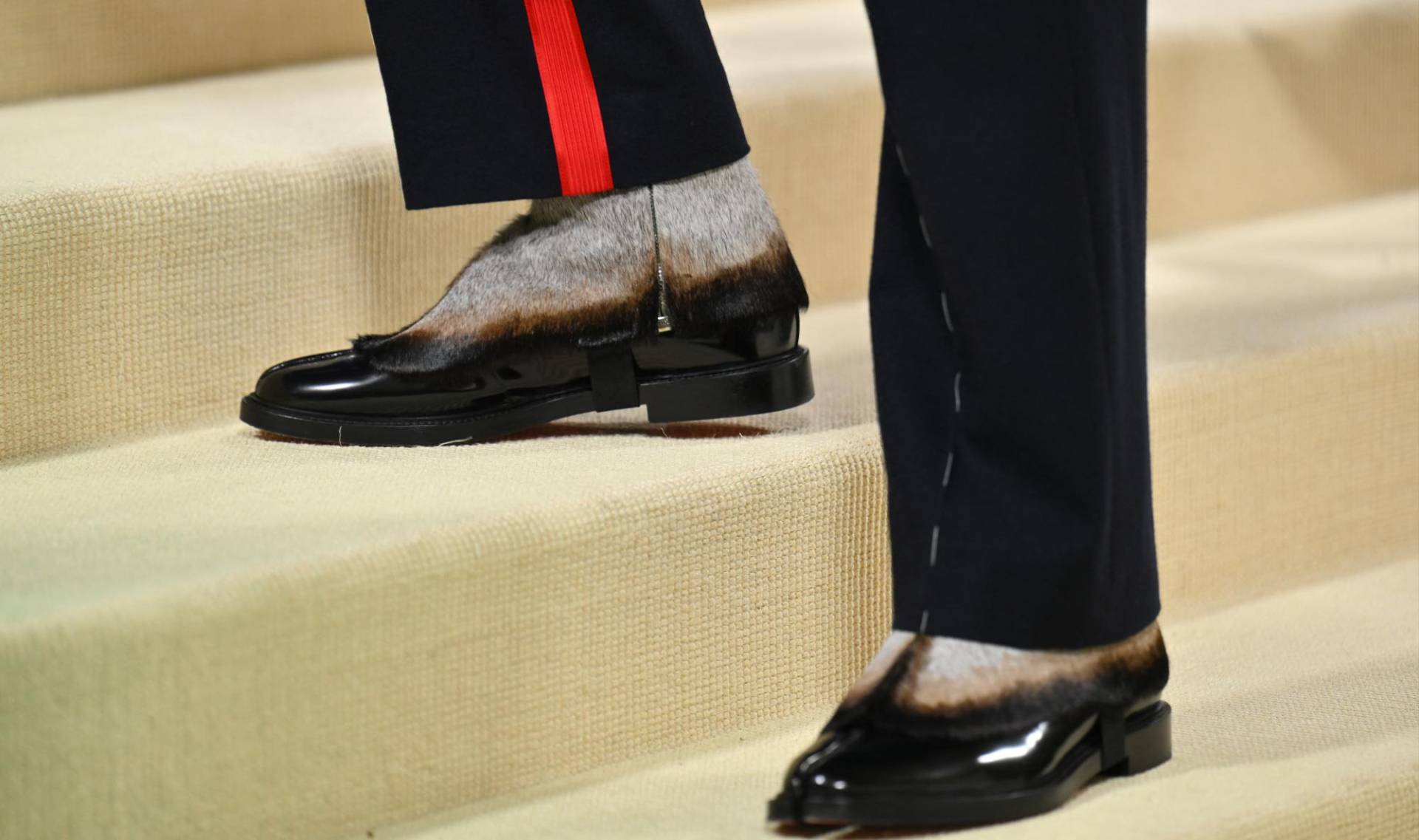 El cantante llevó un pantalón de corte recto con una franja roja y unas botas Tabi que parecen emular las patas de un fauno.