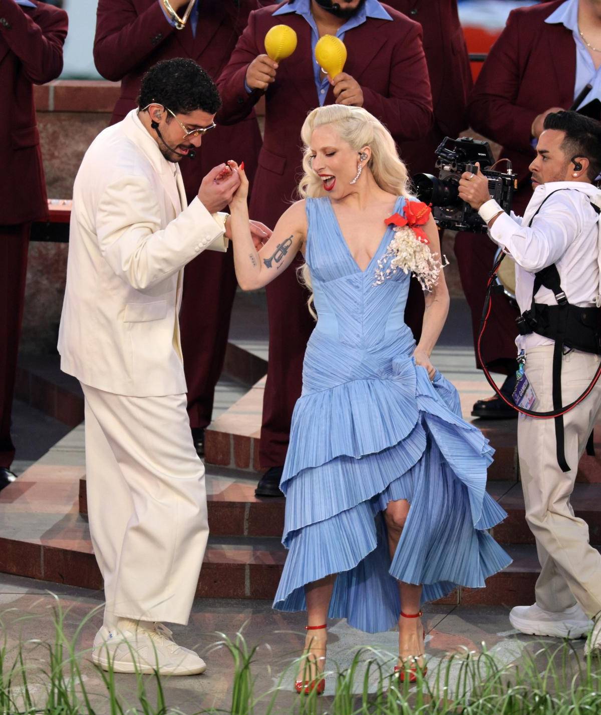 Bad Bunny junto a la cantante estadounidense Lady Gaga, quien lució en el show del medio tiempo del Super Bowl un diseño del dominicano Raúl López, drapeado en el talle, cuello V y falda en vuelos que contrastaban con sus zapatos y manicura roja y su broche de flor de maga