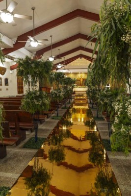 La iglesia Nuestra Señora de Suyapa fue decorada en la entrada principal por un camino de arreglos en bases de metal adornados con baby breath y mucho follaje y un camino espejado.