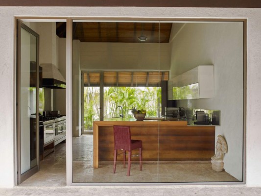 La cocina es de aire minimalista, con puertas de vidrio y rodeada de palmeras