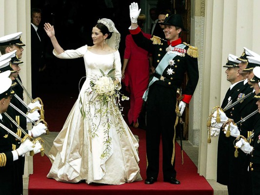Mary Donaldson. El diseñador danés Uffe Fran fue el autor del ajuar que Mary Donaldson vistió el día de su esperada boda con Federico de Dinamarca en mayo de 2004. La novia, de origen australiano, llegó a la Catedral de Nuestra Señora de Copenhague con un espectacular diseño en color blanco nacarado con escote redondo y originales mangas que emulaban la forma de los lirios y una impecable falda de amplio vuelo con pliegues. Casi diez metros de encaje y 24 metros de satén blanco forrado con seda de organza se utilizaron para confeccionar el vestido que se complementó con un velo de encaje irlandés bordado, que fue usado por la bisabuela de Federico, la princesa Margret de Suecia, el día de su boda el 15 de junio de 1905 en Windsor. Además, Mary lucía una tiara, regalo de la reina Margarita de Dinamarca; pendientes de platino, diamantes y perlas de los Mares del Sur, que fueron creados en exclusiva para esa ocasión por la diseñadora de joyas Marianne Dulong y un ramo en cascada con flores de origen australiano y atadas con lazo de seda anudado en la base, que llevaba impresa la fecha de la boda y un monograma de la pareja real.