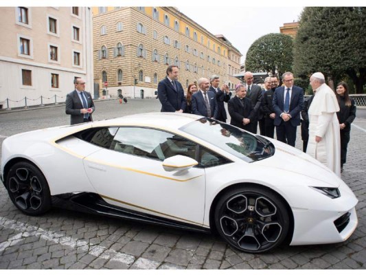 This handout photo taken on November 15, 2017 at the Vatican and released by the Vatican press office, Osservatore Romano shows Pope Francis (R) speaking with Lambhorgini CEO Stefano Domenicali (2ndR) after receiving a Lamborghini Huracan as a gift from the Italian car company. / AFP PHOTO / OSSERVATORE ROMANO / Handout