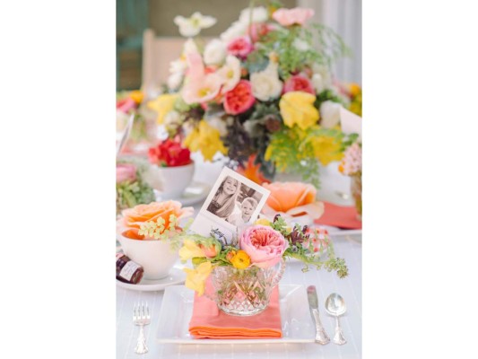 Imprimir fotos de cada invitada con sus hijos o su madre es un detalle que seguramente todas agradecerán. Flores en tonos pasteles sobre mantelería y vajilla blanca completan el setting.<br/>