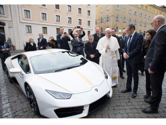 This handout photo taken on November 15, 2017 at the Vatican and released by the Vatican press office, Osservatore Romano shows Pope Francis speaking with Lambhorgini CEO Stefano Domenicali (2ndR) after receiving a Lamborghini Huracan as a gift from the Italian car company. / AFP PHOTO / OSSERVATORE ROMANO / Handout