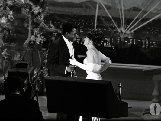 Beso prohibido<br/>Como muchos sabemos, Sidney Poitier se convirtió en el primer afroamericano en ganar la estatuilla a Mejor Actor por su papel en Los lirios del Valle. La bella actriz Anne Bancroft quiso unirse a la celebración de Poitier, dándole un beso en la mejilla. Solo faltó ese gesto para que la gente hiciera un escándalo y tildaran el hecho como ''el beso prohibido''.<br/> <br/>