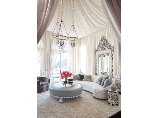 El living tiene un aire surrealista con tergales blancos, sofas seccionales y un ottoman redondo que hace las veces de coffetable.