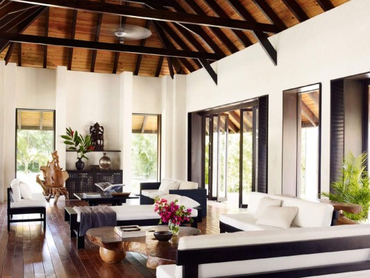 El living de la casa está decorado con sofás de teca y una espectacular mesa de coctel de madera de bosque tropical diseñada por Designers Views