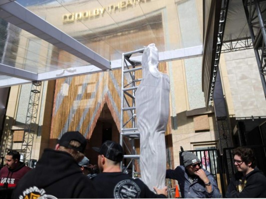 Los trabajadores colocan una de las estatuas decorativas en la entrada principal de la alfombra roja como parte de los últimos detalles de la ceremonia.
