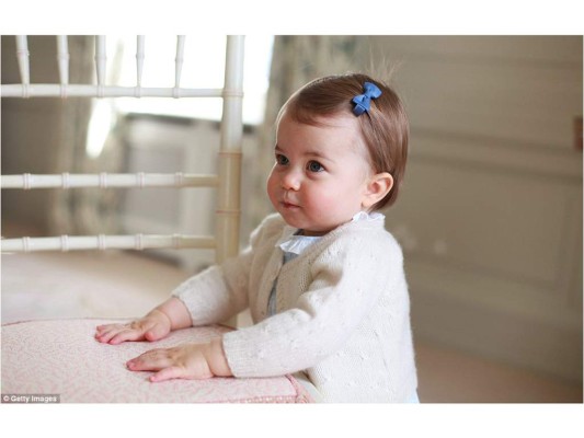 En este imagen, la princesa Charlotte, quien lleva un listón azul en su cabello, se apoya contra una silla
